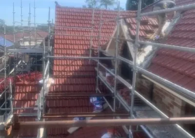 Terracotta tiled roof replacement underway with scaffolding around the property