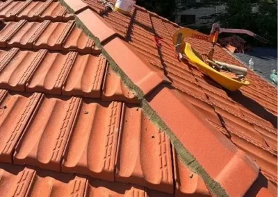 Roofing tools positioned along ridge capping on a terracotta tiled roof