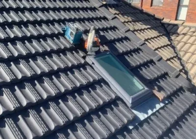 Roofing work being carried out around a skylight on a tiled roof