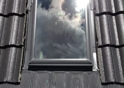 Dark framed skylight installed between roof tiles