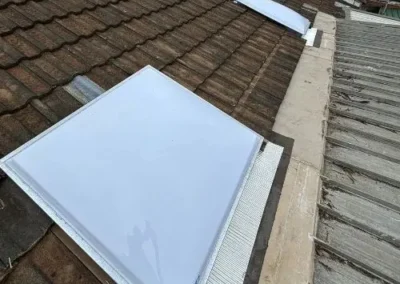 Rectangular skylight fitted into a brown tiled roof