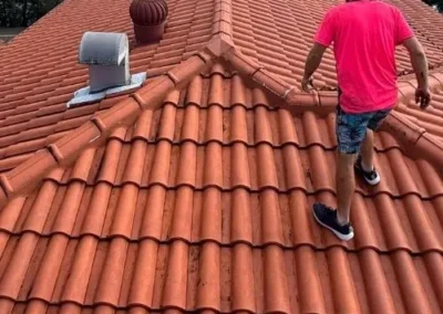 Roofer inspecting and repairing a terracotta tiled roof