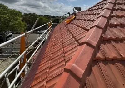 Roofer working along the ridge of a terracotta tiled roof