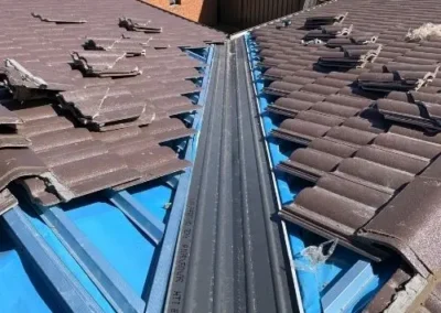New metal valley flashing installed between tiled roof sections